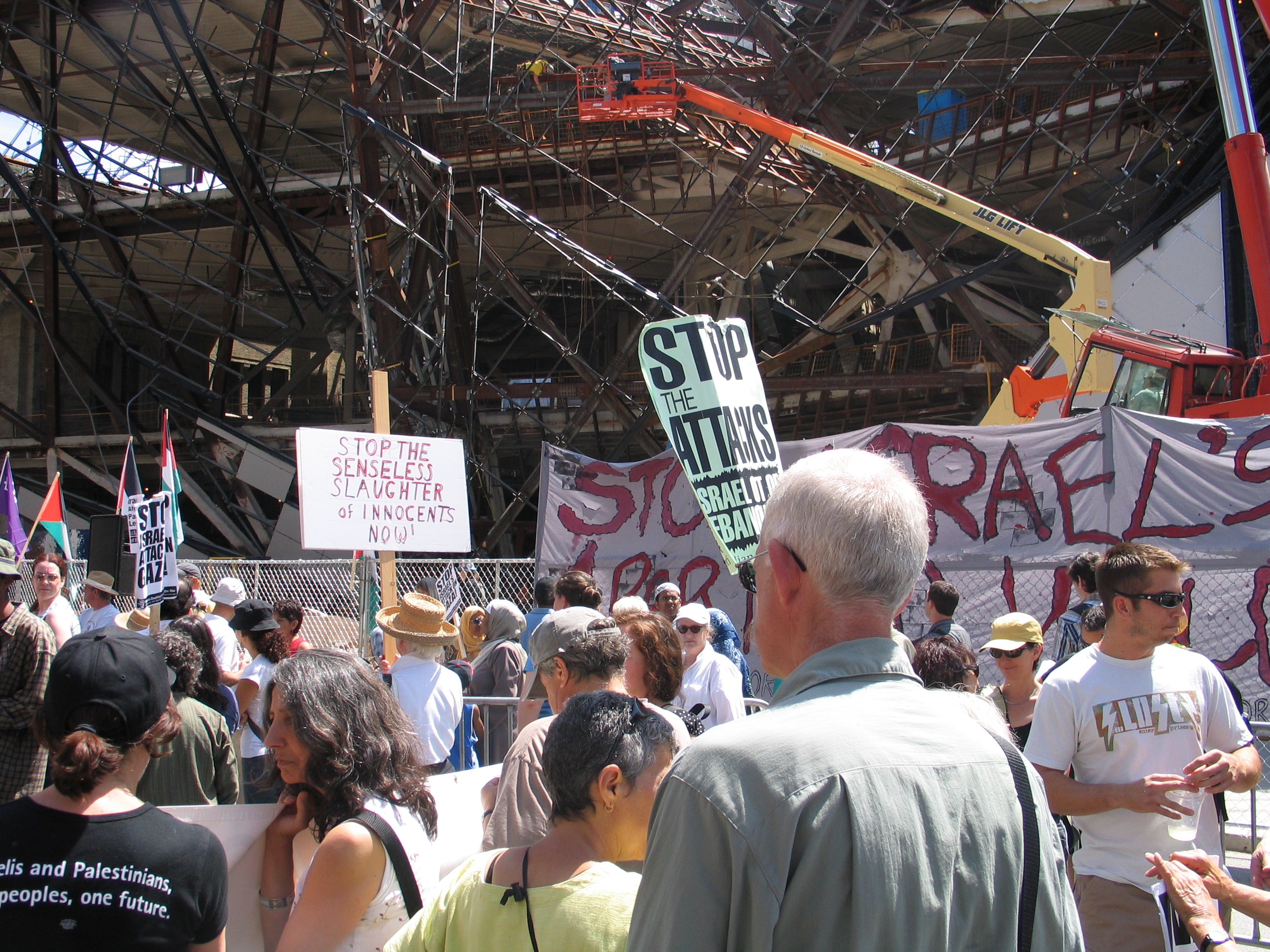 A crowd of people holding protest signs in front of the ROM Crystal, then under construction